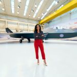 Accelerating Aerospace Innovation: Continual Learning HEA Guide A female engineer stands confidently in front of a modern fighter jet in a hangar.
