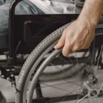 Adaptive Hospital at Home: Autonomous Vehicle Medical Guide A close-up image showing a hand gripping a wheelchair wheel, portraying mobility and accessibility.