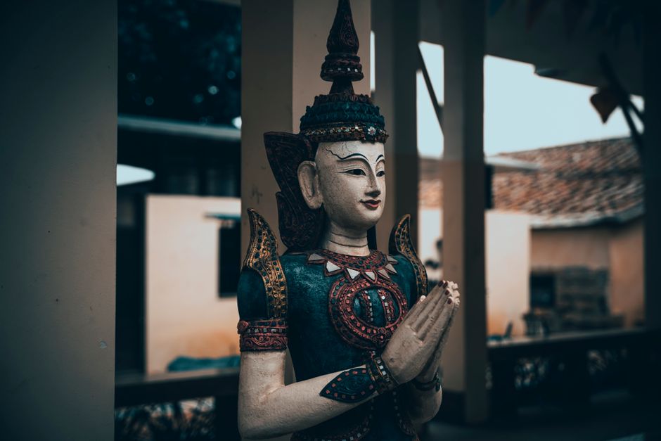 Intricately carved Hindu statue depicting a deity in prayer with detailed ornaments.