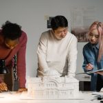 Architects discussing and planning a scale model in a modern office setting.