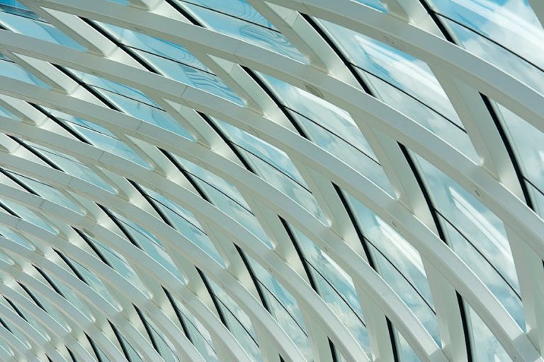 Abstract view of a modern glass and steel ceiling with geometric design and natural light.