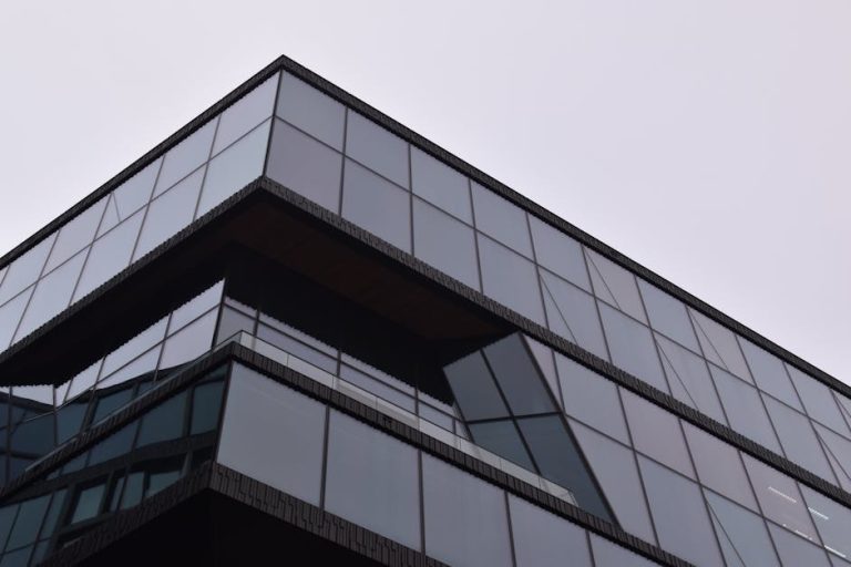 A striking modern building in Amsterdam with a reflective glass facade showcasing sleek architectural design.
