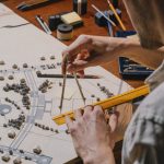 Architecting Scalable Spatial Computing Frameworks for EdTech Architect meticulously working on a detailed scale model with compass and ruler.