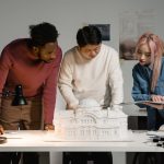 A diverse group of professionals discussing an architectural model in an office setting, emphasizing teamwork.