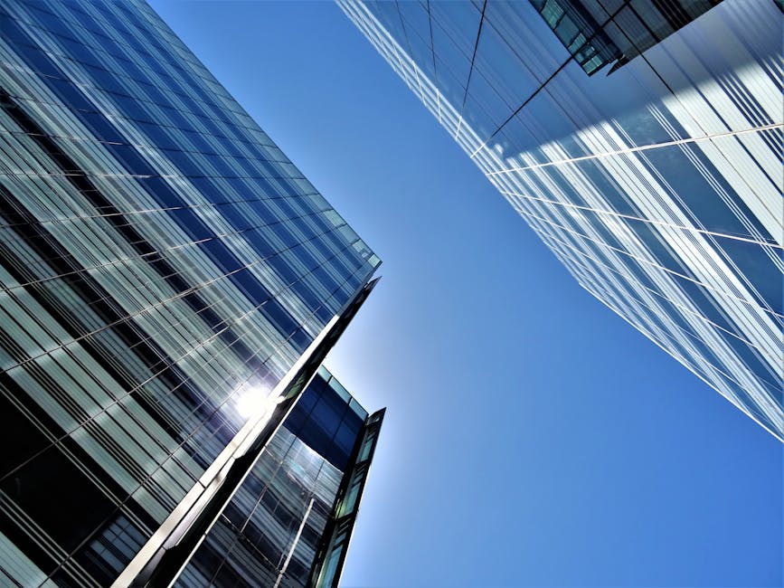 Low angle view of glass skyscrapers reflecting the bright sun in a clear blue sky.