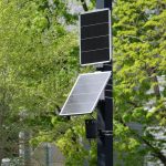 <h1>Balancing Privacy and Power: Energy-Aware Differential Privacy for AR/VR/XR</h1> A modern solar-powered surveillance camera on a street pole amidst green foliage.