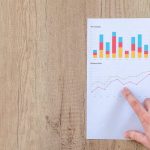 Benchmarking Semantic Web Protocols for Edge and IoT Hand analyzing business graphs on a wooden desk, focusing on data results and growth analysis.