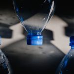 <h1>Beyond the Bottleneck: Few-Shot Post-von Neumann Compilers in Supply Chain Optimization</h1> Artistic close-up of plastic bottles casting intricate shadows on a surface.