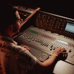<h1>Beyond the Controller: Mastering Multimodal Spatial Computing Control Policies</h1> Audio engineer adjusts controls on professional mixing console in a dimly lit recording studio.