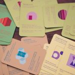 Bio-Inspired Category Theory for Bioelectronics and AI A variety of colorful game cards with geometric shapes scattered across a wooden table.