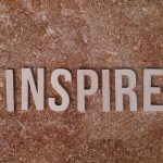 Inspirational word 'INSPIRE' on a textured stone background for motivation.