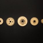 Close-up of golden cogs arranged on a black background showcasing mechanical precision.