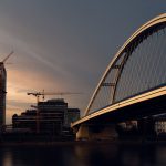<h1>Bridging Privacy and Progress: Continual-Learning Secure Multiparty Computation in Healthcare</h1> A skyline with modern bridge and construction cranes at sunset over a city river.