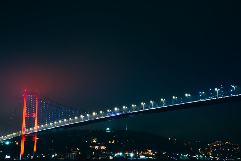 Striking night view of Bosphorus Bridge with vivid lights illuminating Istanbul skyline.
