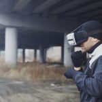 <h1>Bridging the Gap: Simulation-to-Reality Standards for Carbon Removal on Distributed Ledgers</h1> Man wearing VR headset under a bridge, exploring virtual reality outdoors.