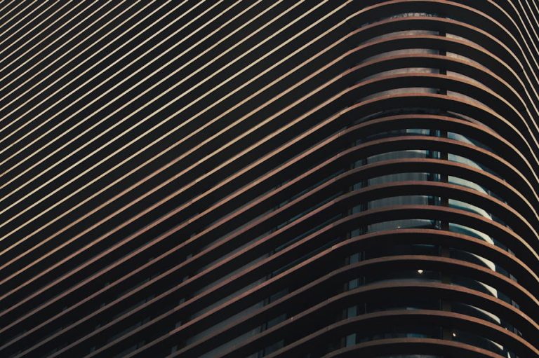 Abstract close-up of a modern building facade featuring a series of curved lines and shadows.