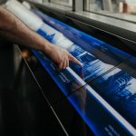 Close-up of a person interacting with a touchscreen display in a modern environment.