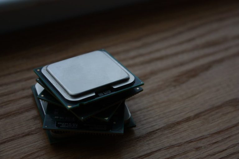 Close-up of multiple computer CPUs stacked on a wooden surface, showcasing technology components.