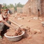 An elderly man works sorting bricks in a rural brick field in Dhaka Division, Bangladesh, illustrating hard labor and resilience.