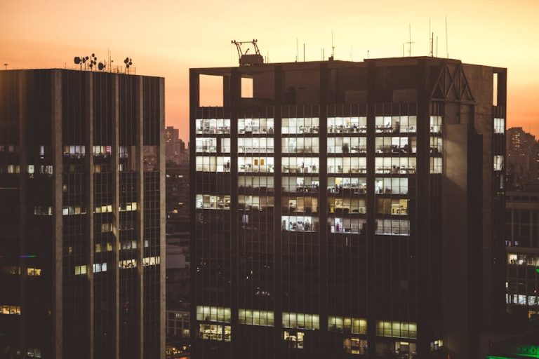 City office buildings illuminated against a sunset backdrop, showcasing urban life.