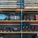 Shelves filled with construction materials like tiles and wood pallets in a warehouse setting.