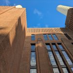 Built for Power: How Architecture Shapes Political Strategy Dynamic perspective of a historic brick industrial building against a clear blue sky.