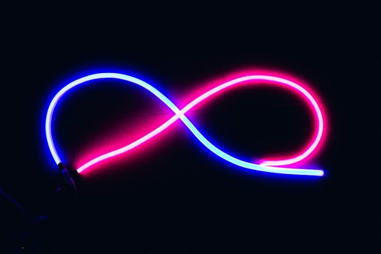 Vibrant neon infinity symbol glowing in blue and pink against a dark backdrop, evoking endless possibilities.