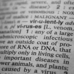 Black and white close-up of a dictionary page focusing on the definition of 'virus'.