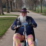 Cloud-Native Adaptive Autonomy for Mathematical Discovery An elderly man with a hat and beard rides a specialized bike in a serene park setting.