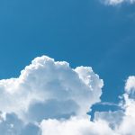 An expansive view of fluffy white clouds set against a clear blue sky, capturing a peaceful nature scene.