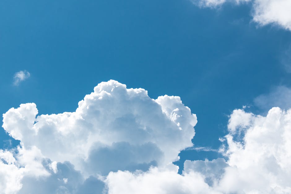 An expansive view of fluffy white clouds set against a clear blue sky, capturing a peaceful nature scene.