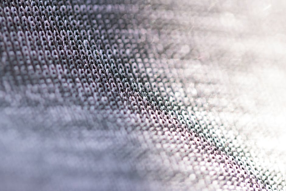 Closeup of fragment of abstract fabric sewn from thin grey threads against blurred background