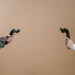 Hands holding game controllers against a brown backdrop, showcasing modern gaming technology.