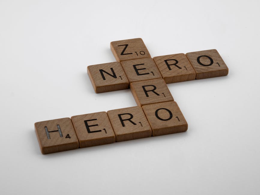 Wooden Scrabble tiles displaying words 'Hero' and 'Zero' on a white surface.