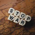 Conflict as Counterpoint: Orchestrating Organizational Dissonance Dice with 'STOP WAR' on a vintage world map signifies peace.