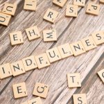 Wooden letter tiles spelling 'mindfulness' on a rustic wood background.