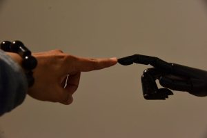 A human hand and a robotic hand extending fingers to touch, symbolizing connection.