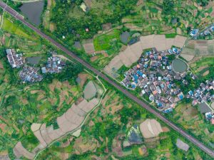 Stunning aerial photo of a rural Chinese village with lush green rice fields and irrigation ponds.