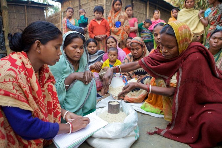 Village women in Bangladesh gather for community development planning and resource distribution.