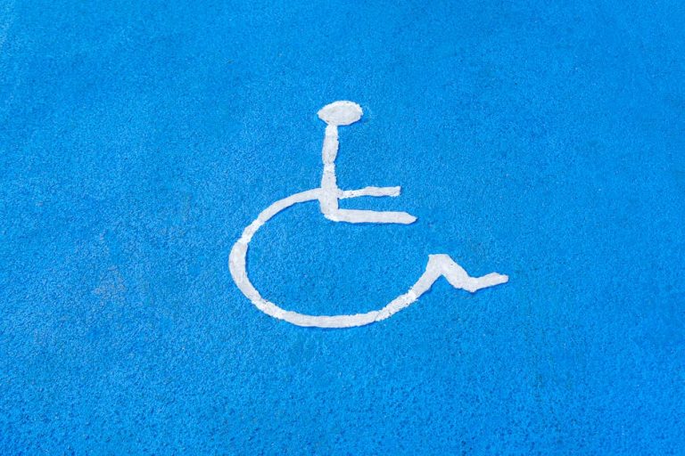 Clear blue disabled parking sign on asphalt surface, symbolizing accessibility.