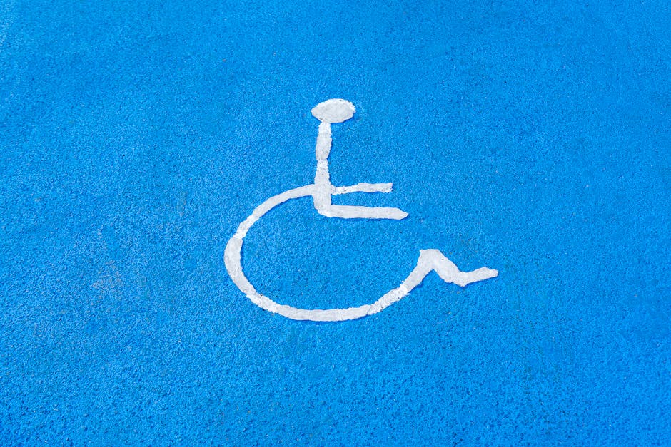 Clear blue disabled parking sign on asphalt surface, symbolizing accessibility.
