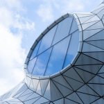 Modern, geometric architectural structure with a unique window design under a bright blue sky.