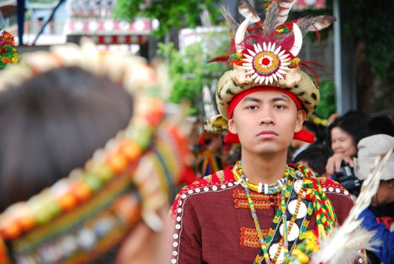 Man in vibrant traditional attire participates in cultural festival parade.