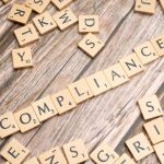 Designing Control Policies for Open-World AI Tutors in XR Wooden letter tiles forming the word 'COMPLIANCE' on a rustic wooden background.