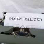Close-up of a vintage typewriter with paper showing the word 'Decentralized'.