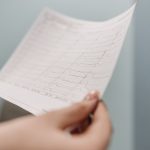 <h1>Designing Interpretable Hospital-at-Home Interfaces: Bridging Clinical Trust and Patient Care</h1> Close-up of a person holding an ECG printout, symbolizing medical diagnosis and health analysis.