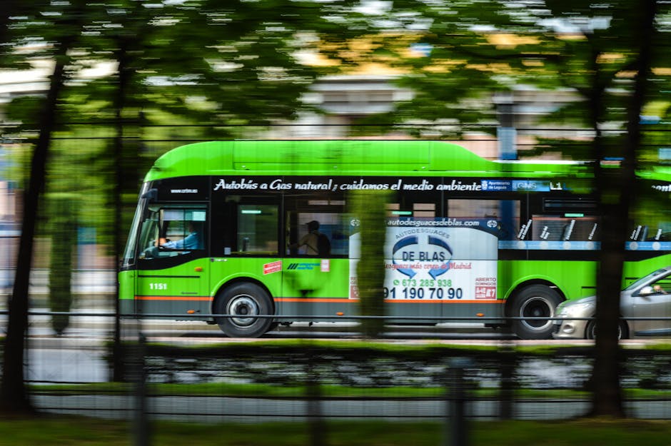 A green natural gas bus in motion on a city street, emphasizing eco-friendly transportation.