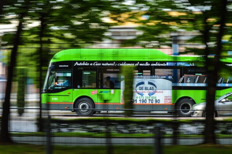 A green natural gas bus in motion on a city street, emphasizing eco-friendly transportation.
