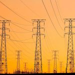 Engineering Resilience: Robust-To-Distribution-Shift Standards Silhouetted power lines against a vibrant orange sunset, symbolizing energy and infrastructure.