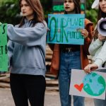 Group of young women at a climate change protest holding handmade signs.